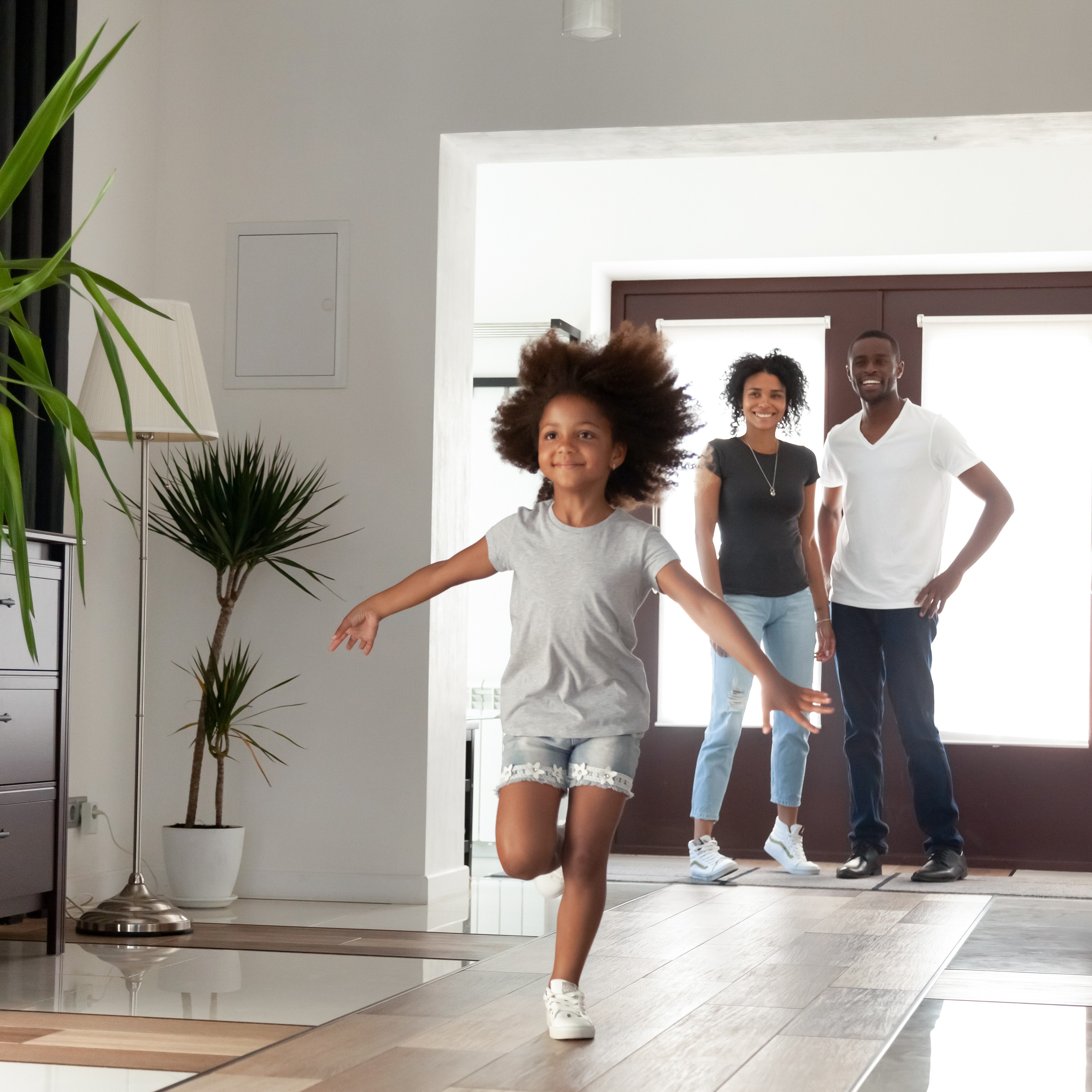 Child running through the house while her parents look on